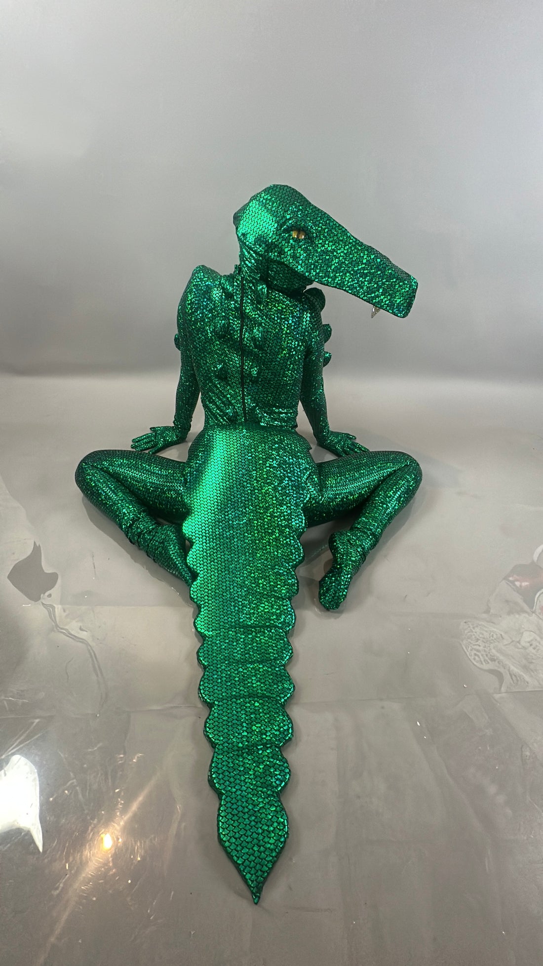 Wearing the Alligator costume—ideal for Halloween or stage shows—a person sits beside a dazzling feather headpiece, offering perfect inspiration for your next performance outfit or TV filming accessory.
