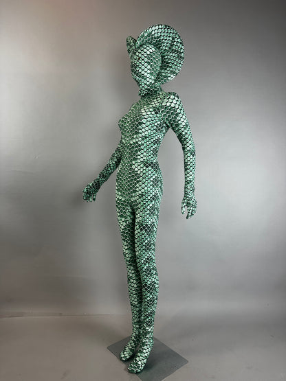 A mannequin wears the Green pixel Cobra Costume, a snake print catsuit with a custom headdress, Serpent Cosplay unitard for contortionists or dancers, standing against a gray background.