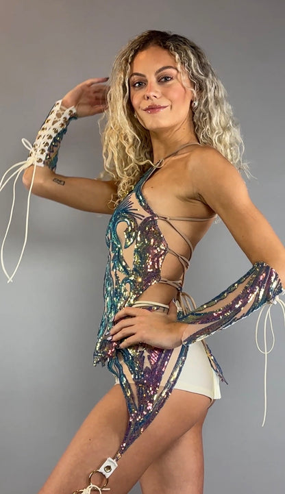 A woman models the Chaps pants and laced top festival costume set, featuring sparkling sequins and matching arm accessories, striking a confident pose against a plain gray background.