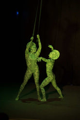 Two performers in Green pixel Cobra Costumes—a snake print catsuit with headdress—pose on stage with aerial straps, their serpent cosplay dance unitards shimmering under the lights against a dark background.