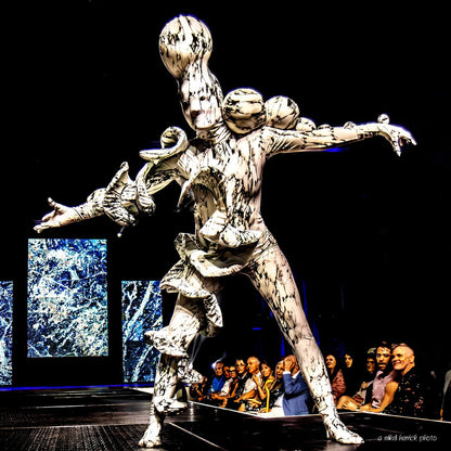 A model in the Mushroom Creature Costume—an avant-garde, white and black marble print spandex full body suit with large sculptural forms—walks on a fashion runway.