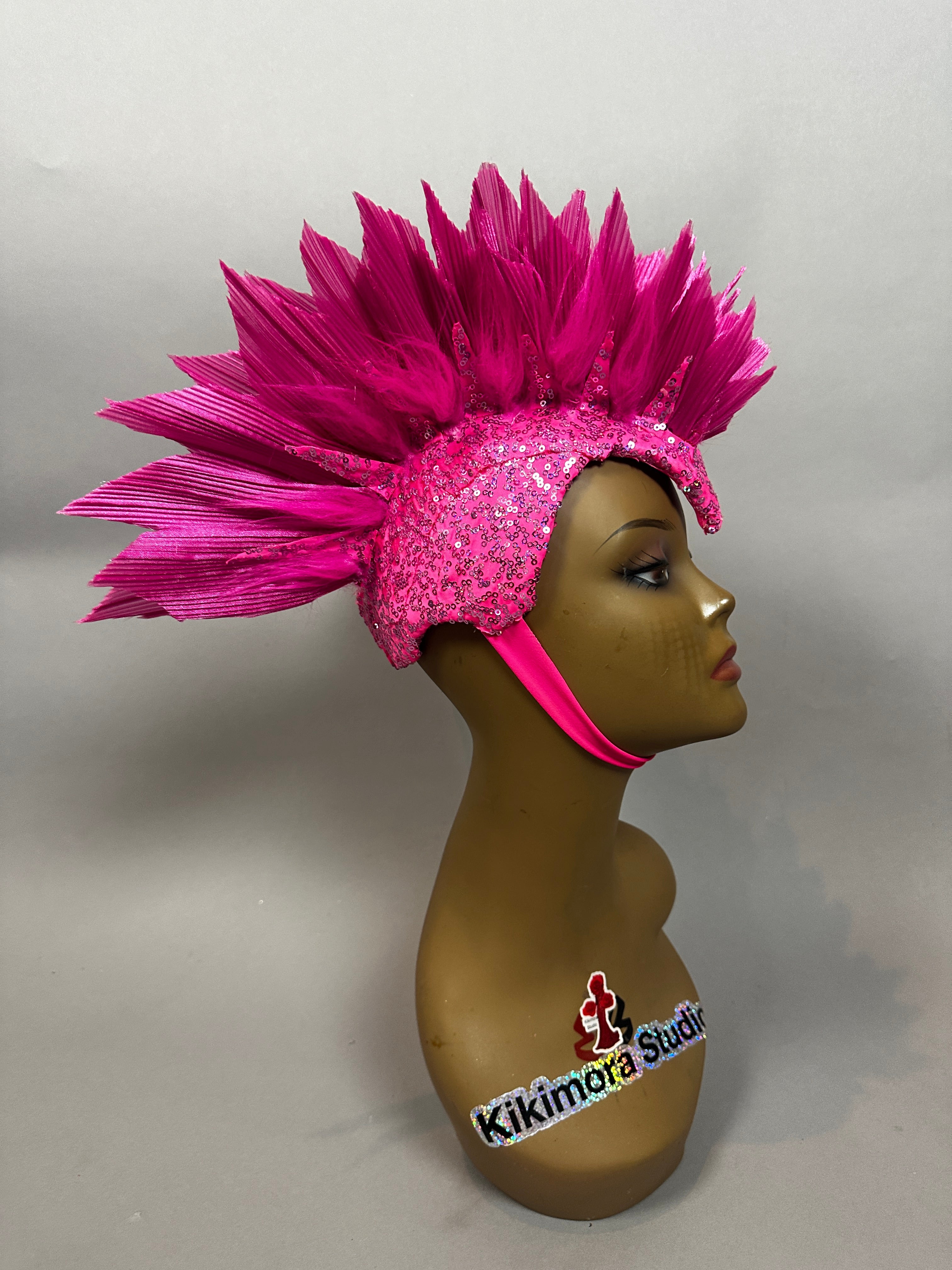 A mannequin head displays the "Pink Bird Headpiece," a fairy hat and theatrical headwear for aerialists, featuring bright pink spikes, a chin strap, and decorative sequins.
