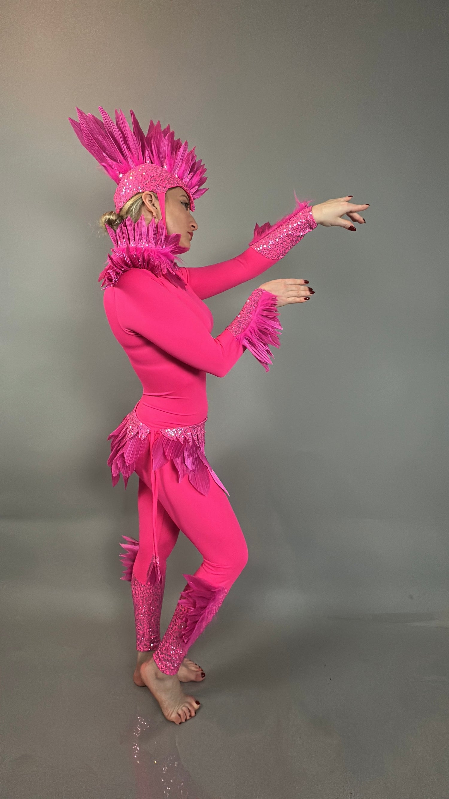 Model wearing the Pink bird full costume for aerial gymnastics, dancers, and TV productions, featuring vibrant feathers and a bold headpiece, posed against a plain gray background.