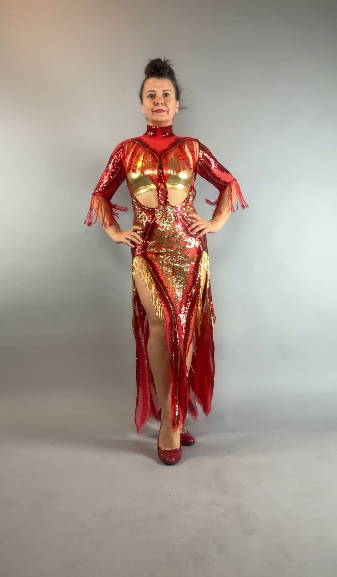 Woman wearing the bearded French accessories Sequin Sheer Dress—backless, with beaded fringe accessories—poses elegantly against a plain gray background.