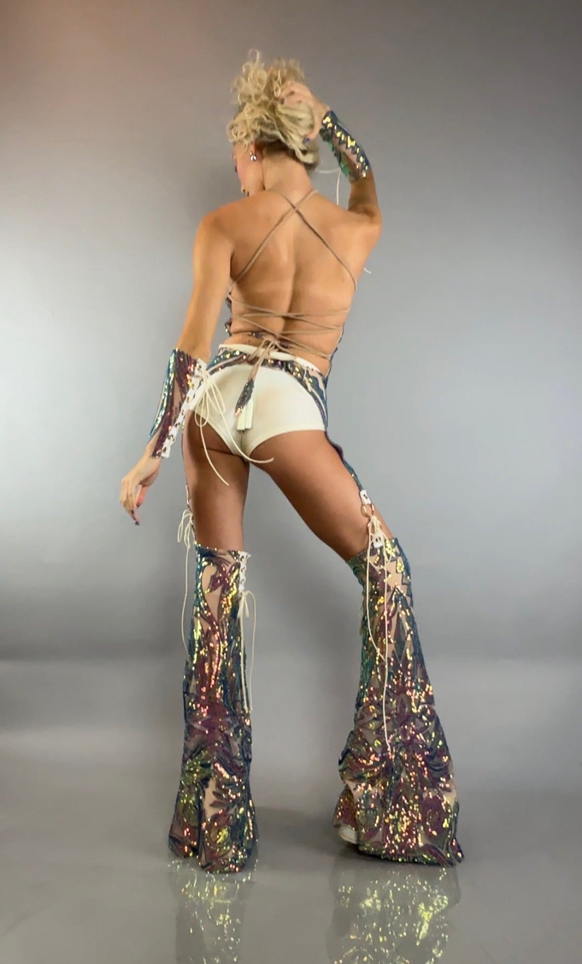 Turn heads in this dazzling festival costume set featuring sparkly sequin chaps pants, a laced strappy top, coordinating white bottoms, matching arm warmers, and high-heeled boots—the perfect sequins performance outfit for standout moments.