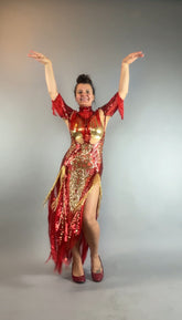 Woman wears the bearded French accessories Sequin Sheer Dress—backless, with beaded fringe—posing with arms raised and smiling against a plain gray background.
