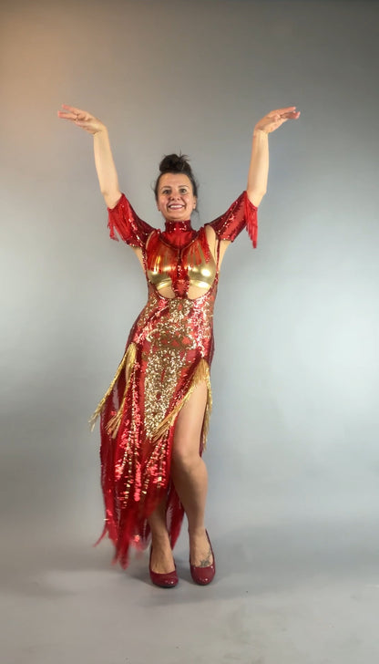 Woman wears the bearded French accessories Sequin Sheer Dress—backless, with beaded fringe—posing with arms raised and smiling against a plain gray background.