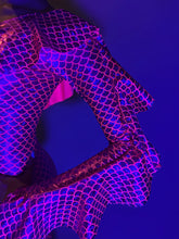 A person wears the Red Ruffle Catsuit featuring an off-shoulder spandex design and asymmetrical ruffles, posing against a blue background.