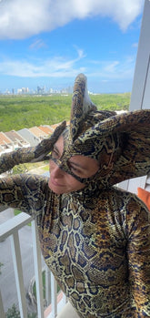 Wearing the custom Green Cobra Snake Costume, a person in a shiny spandex catsuit with a dramatic snake headpiece stands on a balcony, overlooking the city—perfect for gymnastics, acrobatics, dancers, and contortionists.