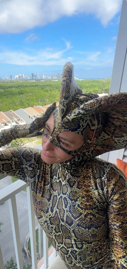 Wearing the custom Green Cobra Snake Costume, a person in a shiny spandex catsuit with a dramatic snake headpiece stands on a balcony, overlooking the city—perfect for gymnastics, acrobatics, dancers, and contortionists.