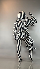 Person in a Black and White Striped Creature Costume with large, sculptural circular and pleated accents.