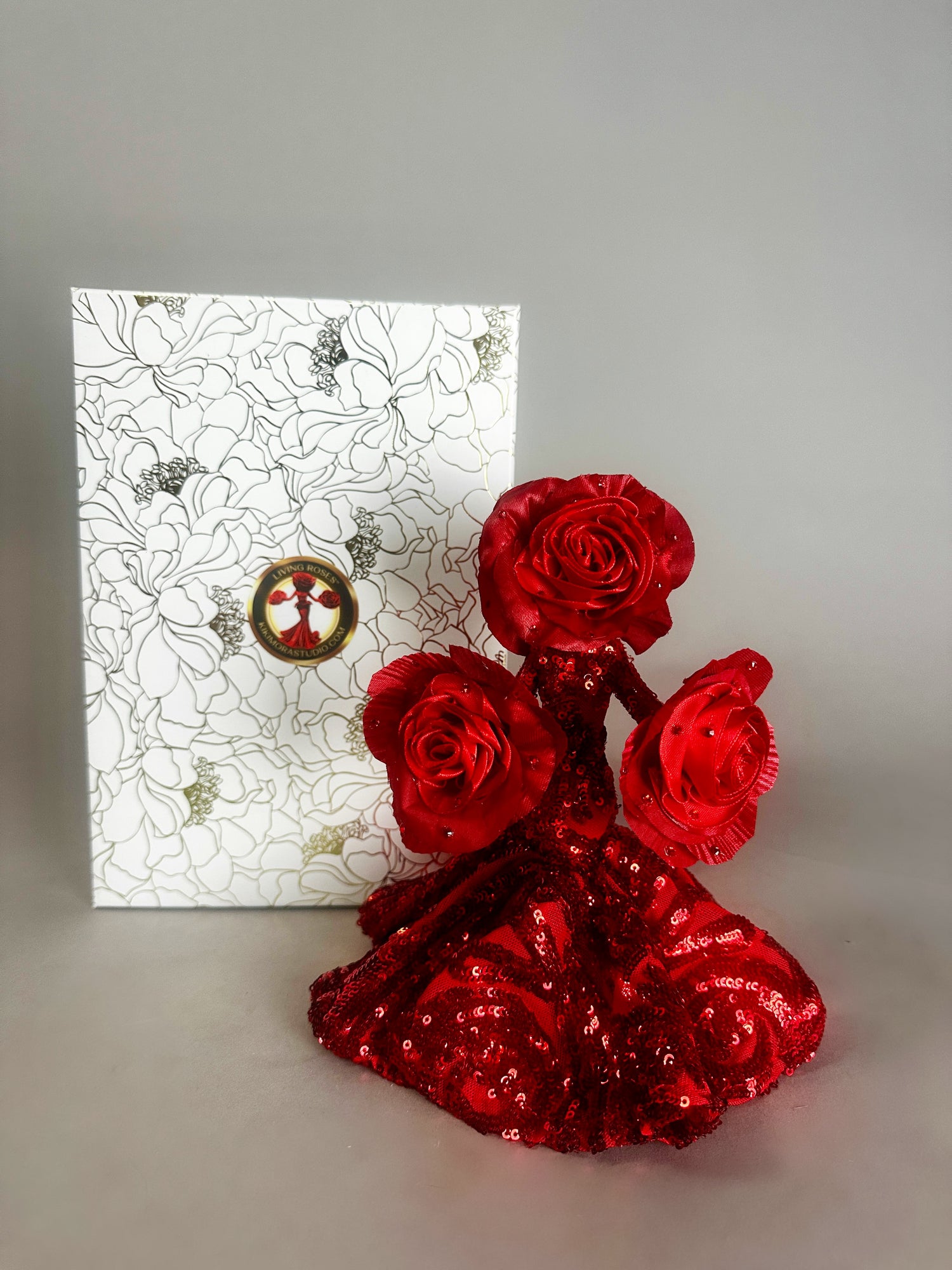 The Mini Living Rose sculpture by Kikimora Studio is a handcrafted doll ornament shaped like a red rose dress, displayed before a floral white box for a magical art touch.