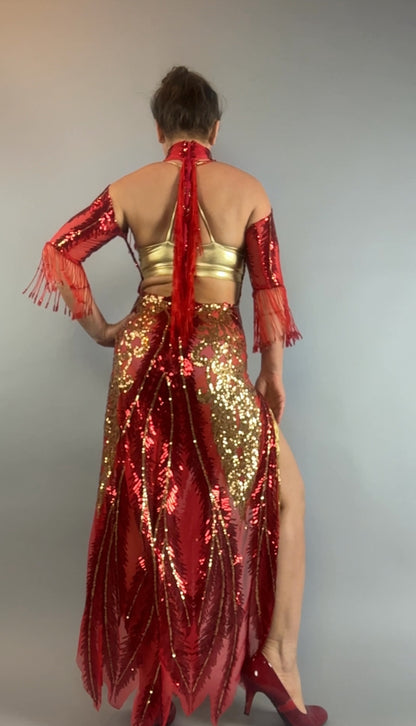 Person wearing the bearded French accessories Sequin Sheer Dress, a backless red maxi with gold beaded fringe, standing with their back to the camera against a gray background.