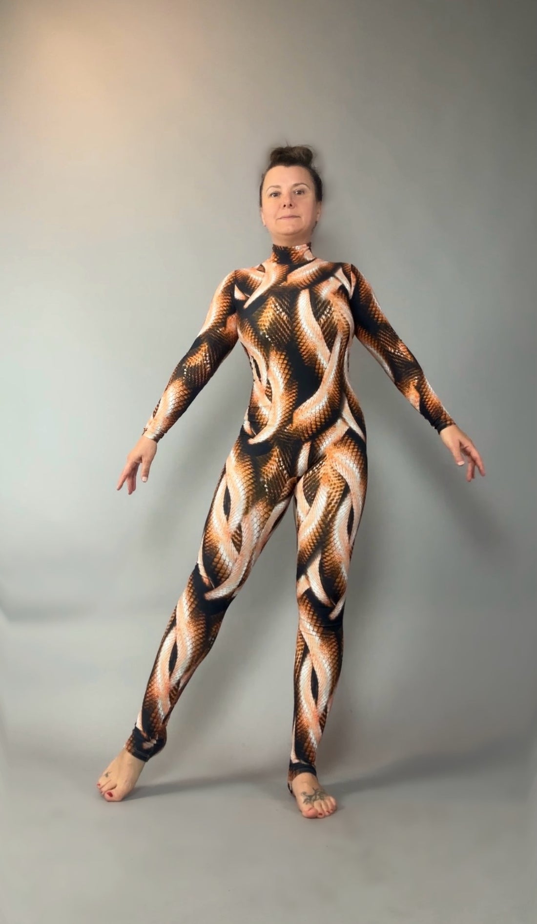 Front view of a brown, black and cream snake-print catsuit with a turtleneck, long sleeves and full-length legs.