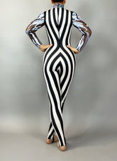 A person wearing the Glamorous sequins Stripes Catsuit costume, featuring black and white stripes with sheer patterned sleeves and a sequined leaf design, is standing with their back to the camera.