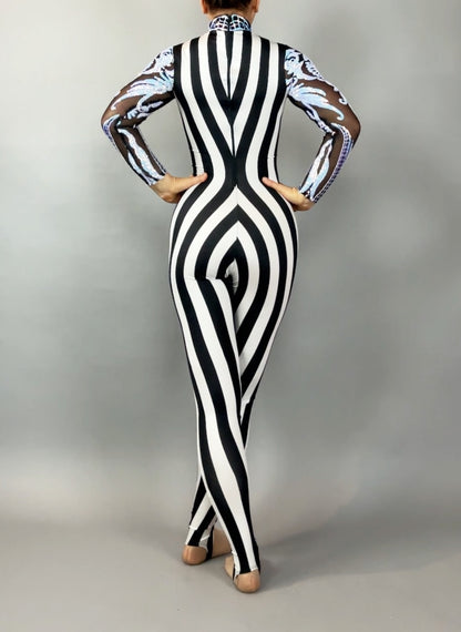 A person wearing the Glamorous sequins Stripes Catsuit costume, featuring black and white stripes with sheer patterned sleeves and a sequined leaf design, is standing with their back to the camera.