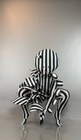 A person in a Black and White Striped Creature Costume with Sculptural Details, featuring a round, sculpted headpiece.