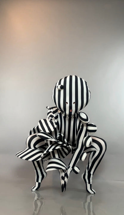A person in a Black and White Striped Creature Costume with Sculptural Details, featuring a round, sculpted headpiece.