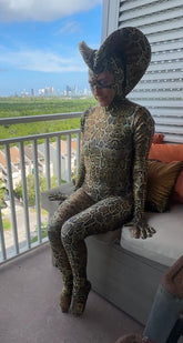 Person wearing the Green Cobra Snake Costume—perfect for gymnastics, acrobatics, dancers, or contortionists—poses on a balcony with a city view in the background.