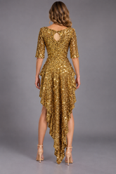 A woman stands facing away against a plain gray background, modeling the Gold Sequin Leotard with back cutout—an eye-catching showgirl costume and dance competition wear featuring a halter neck and dramatic high-low hemline.