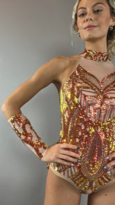 A person wears the Fire color sparkling Halter Leotard with sequin accents and detachable sleeves, standing confidently against a plain background.