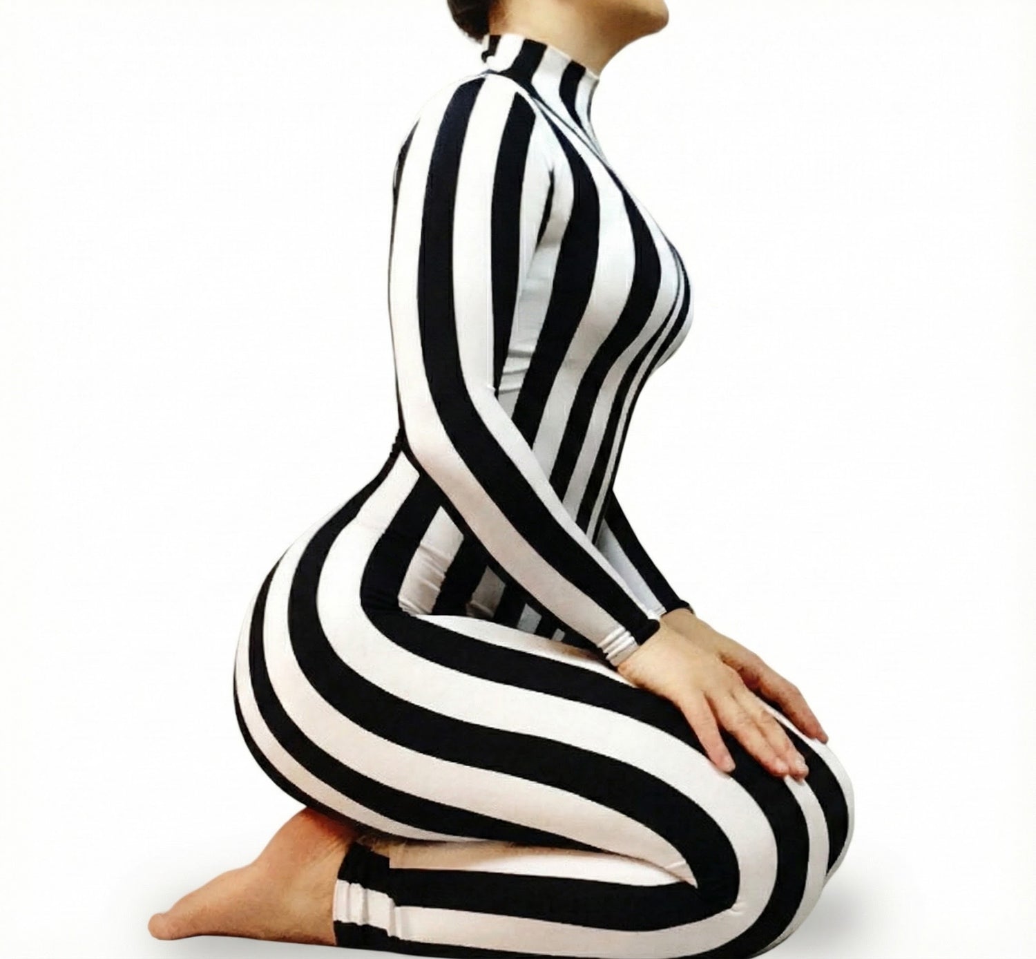 Model kneeling in a Black and White Striped Catsuit with full sleeves and turtleneck, designed to contour the body, against a white background.