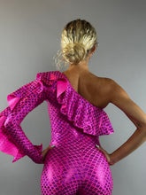 Person with blonde hair in a bun wears the Ruffle Catsuit, an off shoulder spandex jumpsuit featuring asymmetrical ruffles and a custom color scale pattern for a glamorous mermaid-inspired look.
