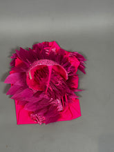 A vibrant pink bird full costume for aerial gymnastics, dancers, and TV productions with textured, shiny, and feathery details is displayed folded on a plain gray background.