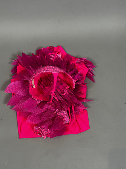 A vibrant pink bird full costume for aerial gymnastics, dancers, and TV productions with textured, shiny, and feathery details is displayed folded on a plain gray background.