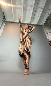 A person poses confidently in a full-body Brown Snake print Catsuit featuring a turtleneck and long sleeves, showcasing the bold metallic animal pattern against a plain backdrop.