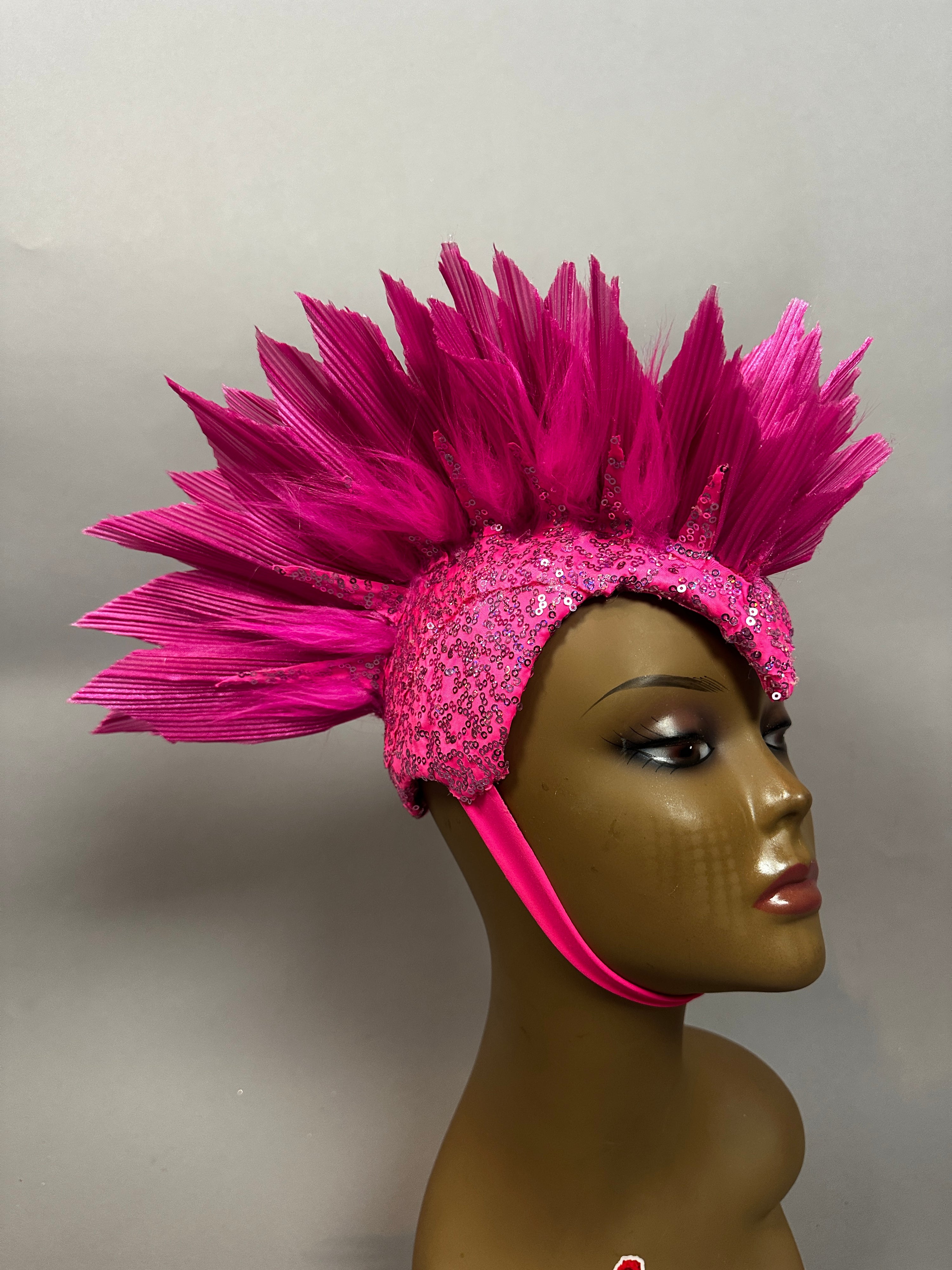 Mannequin head displays the Pink Bird Headpiece, a bright pink sequined fairy hat with butterfly accents, chin strap, and theatrical aerialist design, set against a plain background.