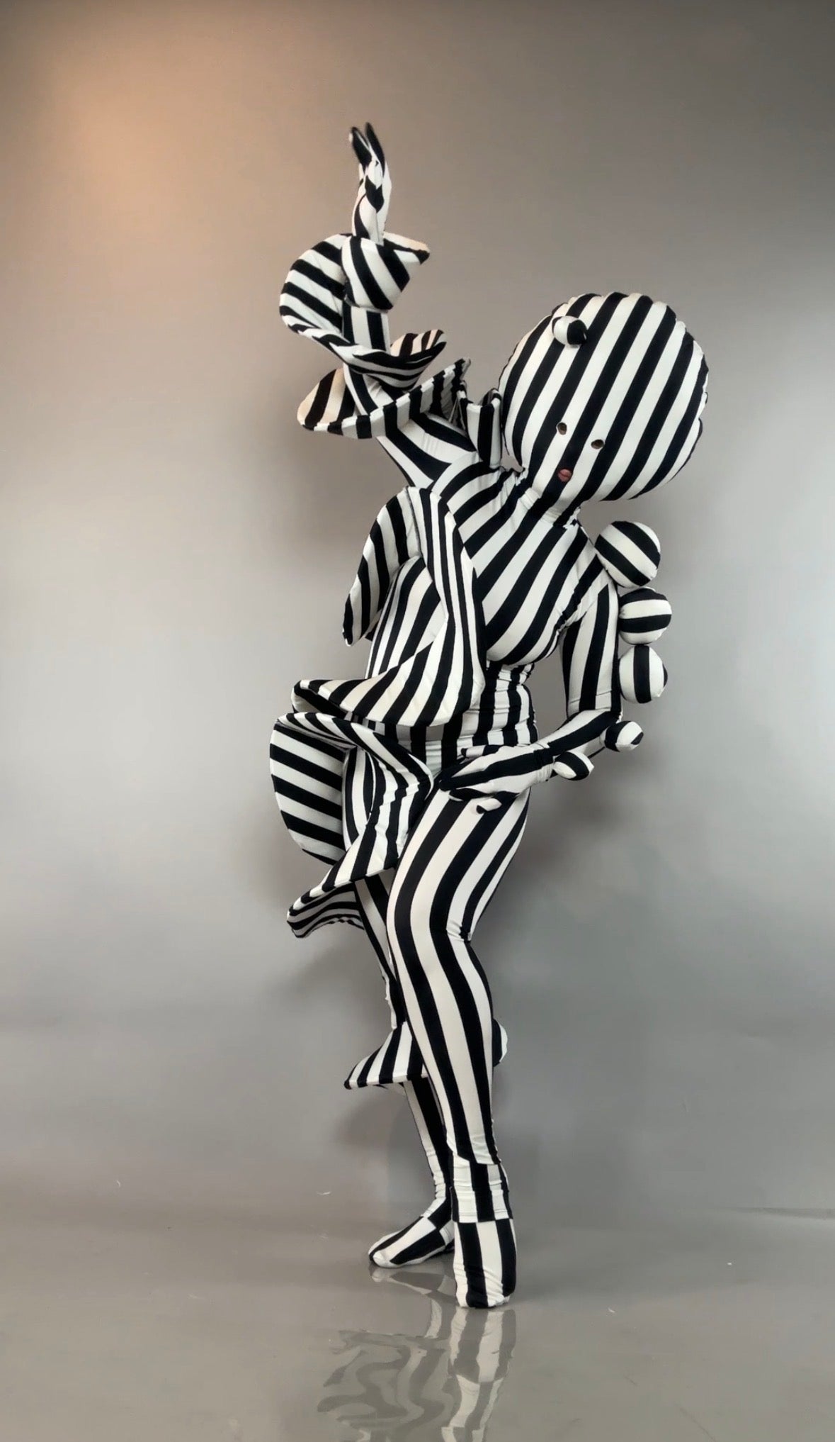 Black and White Striped Creature Costume with Sculptural Details featuring a striped bodysuit, spheres, and flourishes.
