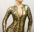 A person poses confidently in the Catwoman Bodysuit Costume, an exotic dancewear party outfit made from beautiful gold and black patterned spandex with a deep neckline and 4-way stretch, set against a plain background.