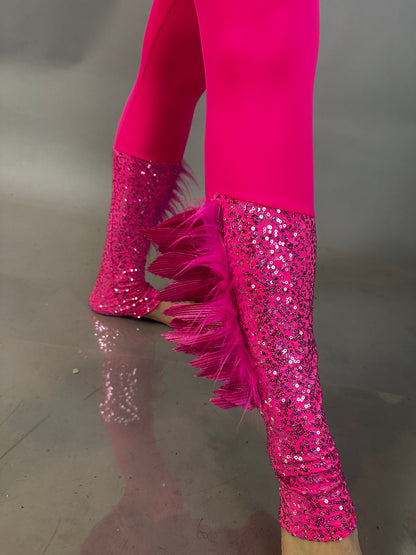 A person confidently wears the Pink Bird full costume for aerial and dancers, featuring bright pink sequin leggings with feather trim, standing on a reflective surface.