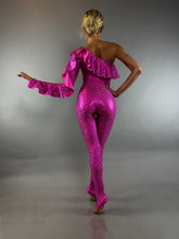 A woman wearing a Red Ruffle Catsuit—an off-shoulder, asymmetrical spandex jumpsuit in custom colors—stands barefoot against a gray background.