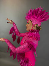 A person in profile wears the Pink bird full costume for aerial and dancers, featuring bright pink feathers and sequins, striking a dramatic pose with raised arms.