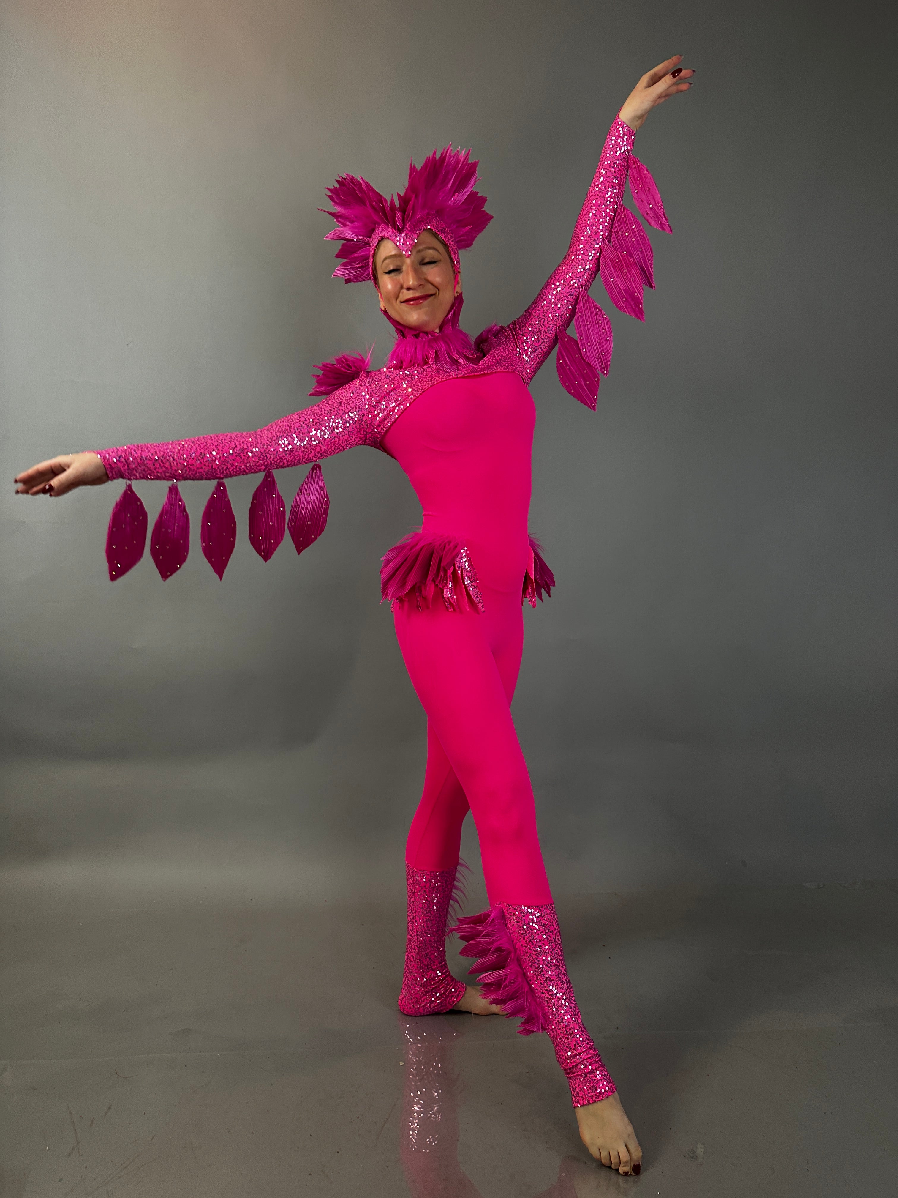 A performer in the Pink bird full costume for aerial and dancers poses with arms raised, featuring a feathered headpiece and sparkly accents—ideal for theatrical shows or stage performances.
