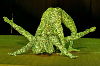 Two contortionists in Green pixel Cobra Costume snake print catsuits pose in an intricate, flexible formation on stage, showcasing the custom-made Serpent Cosplay dance unitard and headdress.
