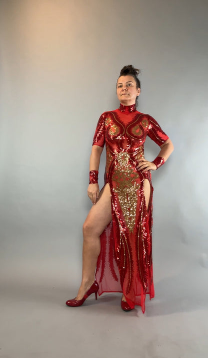 Woman in a Red and Gold Sequin Sheer Dress, sleeveless with hand accessories, poses confidently against a gray backdrop.