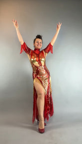 Woman wears the bearded French accessories Sequin Sheer Dress—backless with a thigh-high slit and beaded fringe—posing with arms raised and smiling against a plain background.