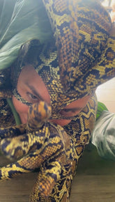 A person in a Green Cobra Snake Costume with a striking headdress, perfect for gymnastics, dance, acrobatics, or contortionists, reaches toward the camera and locks eyes intensely. Custom made uniform included.
