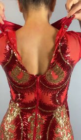 Person zipping up the Red And Gold Sequin Sheer Dress, a sleeveless maxi style with gold accents, shown from the back while wearing hand accessories.