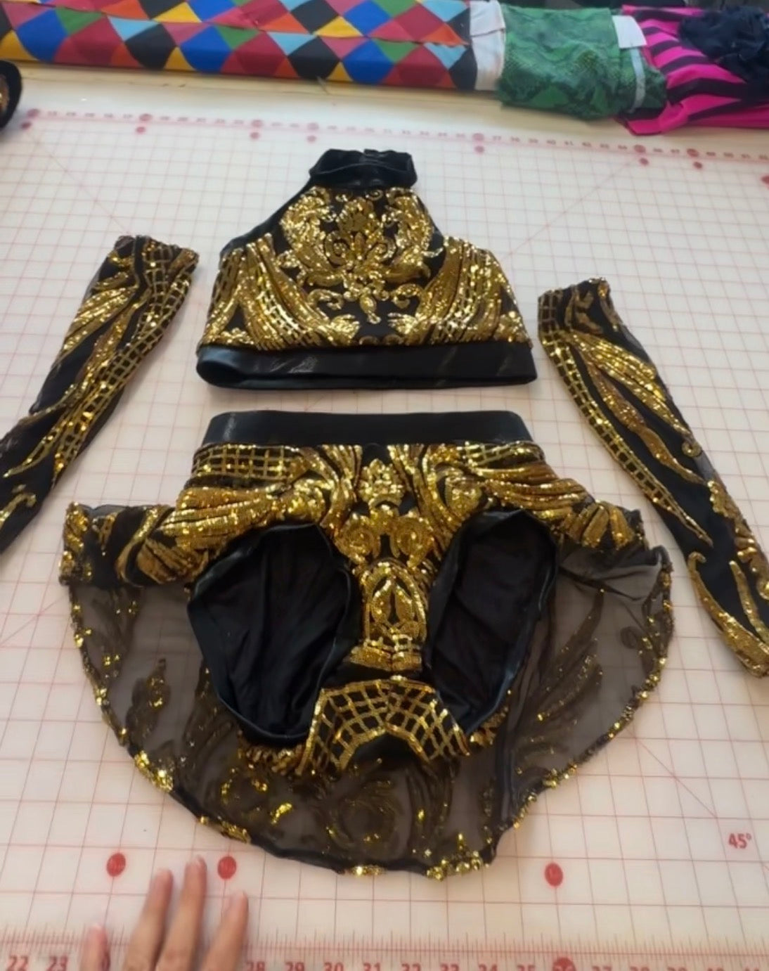 Introducing the Gold Sequin on Black Crop Top and Bottom Set—a dazzling halterneck top paired with skirted bottoms and coordinating hand accessories. This dance costume shines with shimmering golden sequins set against sleek black mesh, creating an elegant and eye-catching stage ensemble.