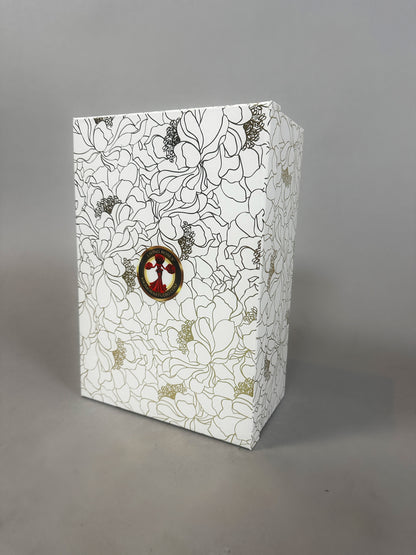 White box with black and gold floral pattern, featuring a small circular bird illustration on the front—packaging for the Mini Living Rose sculpture doll ornament from Kikimora Studio.