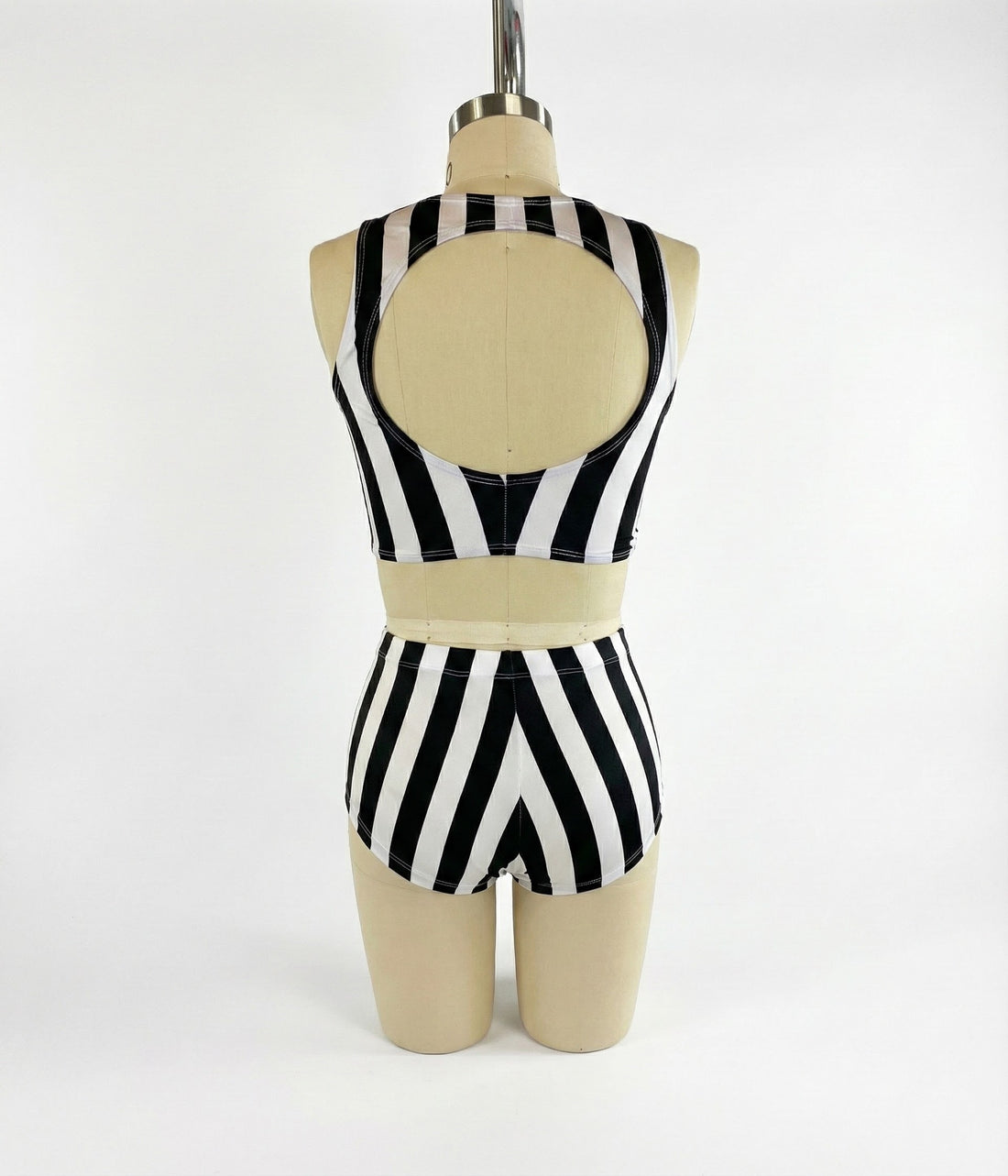 A mannequin wears the Exotic Dance Costume—black and white striped crop top with high-waisted bikini bottoms—shown from the back, perfect as a trending festival outfit.