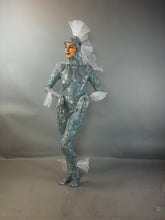 Model wearing the "Sea Creature" costume, featuring shimmering silver fabric and fin-inspired details, highlights couture design against a gray background.