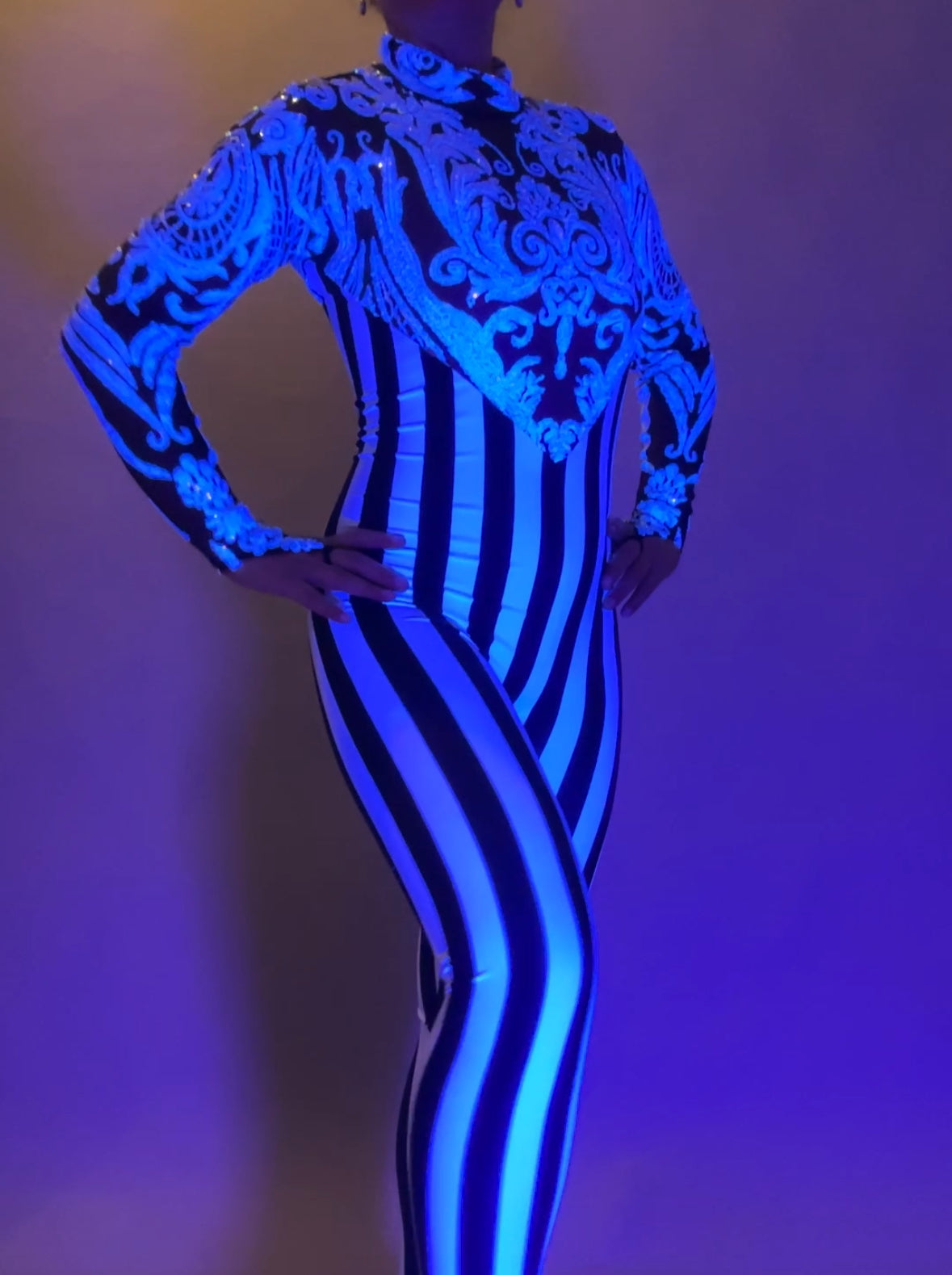 Wearing the Glamorous Sequins Stripes Catsuit—featuring bold blue patterns and vertical black and white stripes—is perfect for festivals or as a striking stage costume.