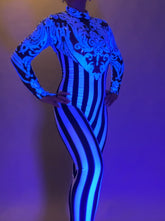 Wearing the Glamorous Sequins Stripes Catsuit—featuring bold blue patterns and vertical black and white stripes—is perfect for festivals or as a striking stage costume.