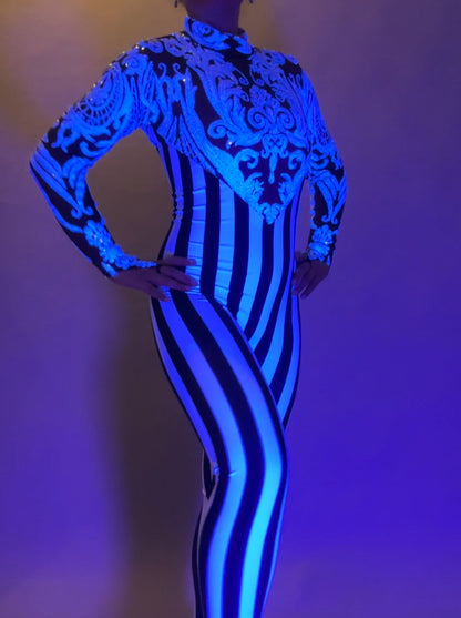 Wearing the Glamorous Sequins Stripes Catsuit—featuring bold blue patterns and vertical black and white stripes—is perfect for festivals or as a striking stage costume.
