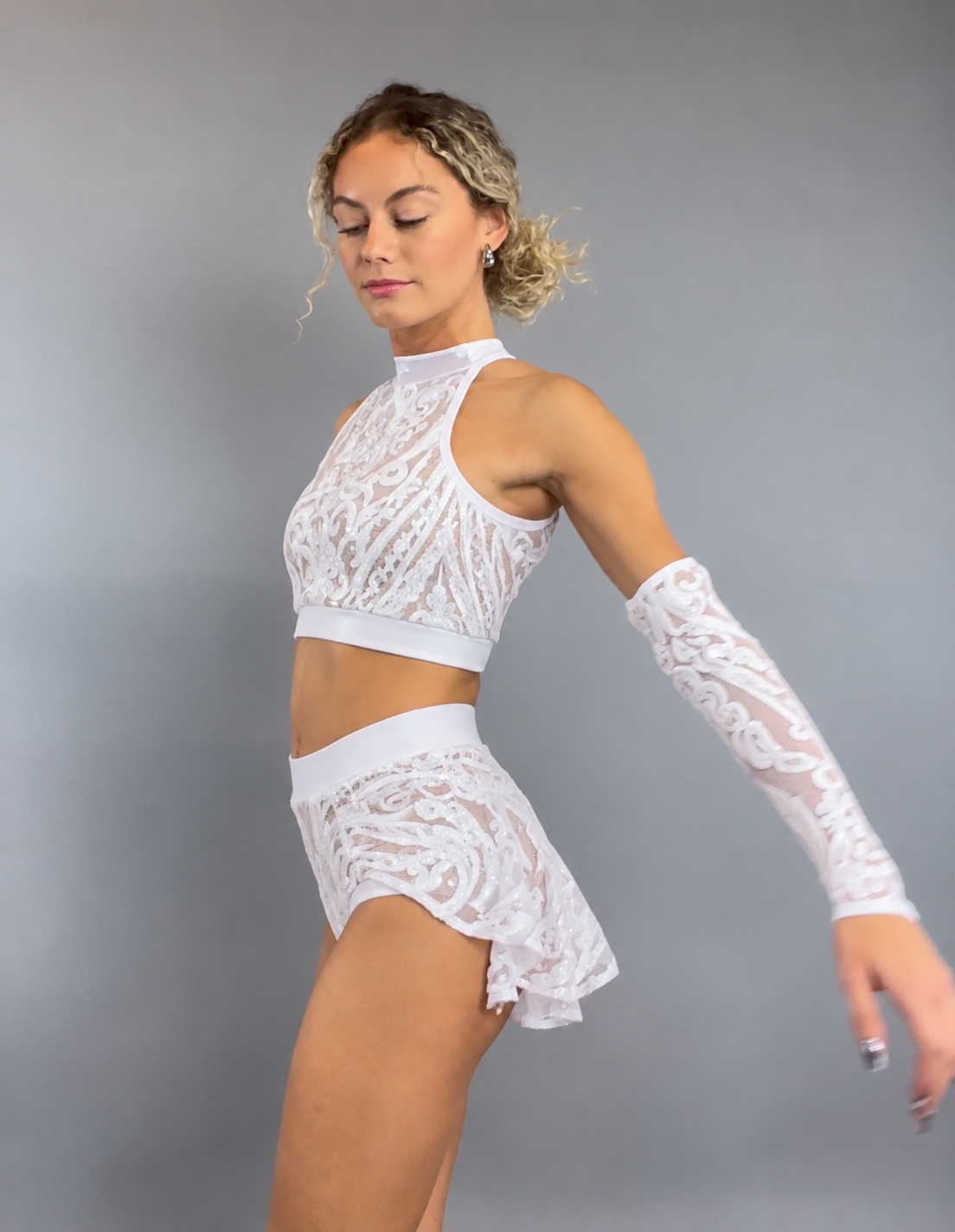 Woman in White Sequin on white Crop Top and Bottom Set poses gracefully against a plain gray background.